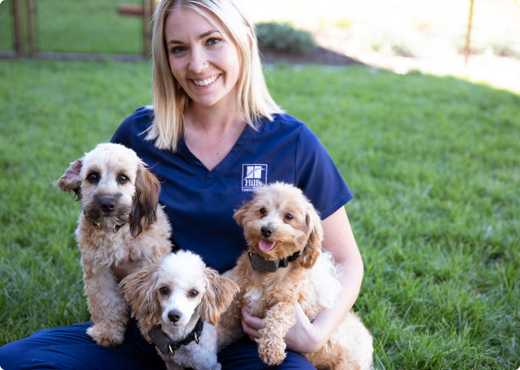 Εργαζόμενη της Hill's Pet κρατάει στην αγκαλία της τρία κουτάβια